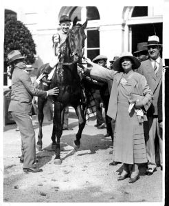 TWENTY GRAND is led in by his owner, Mrs. Payne Whitney, after winning the 1931 Belmont Stakes. The colt also won the Kentucky Derby that year.